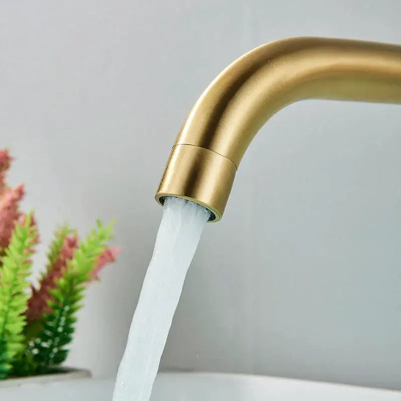 Modern brushed gold and black wall mounted basin faucet with brass finish sleek curved design and flowing water stream