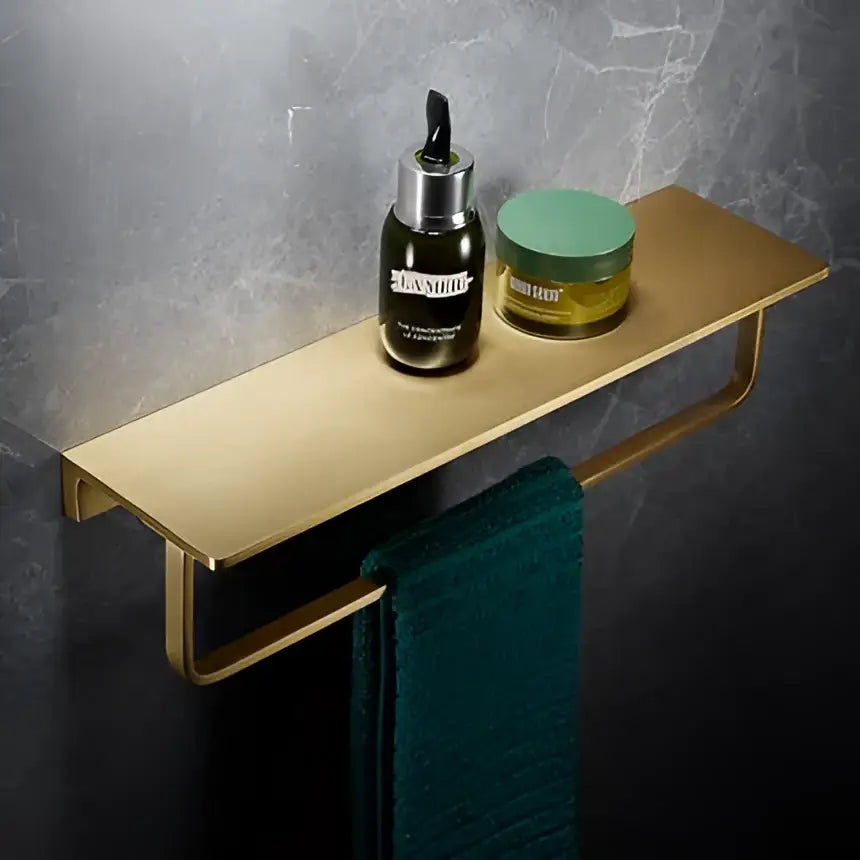 Modern brushed gold brass wall-mounted bath hardware set with integrated towel bar holding la mer bottle and jar