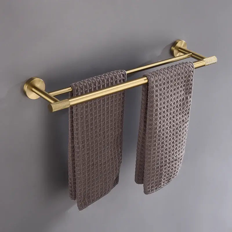 Modern brushed gold double towel rack in bathroom accessories set holding two gray waffle-weave towels