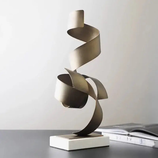 A sleek brushed gold geometric wrought iron sculpture with smooth curves on a minimalist white base for living room decor