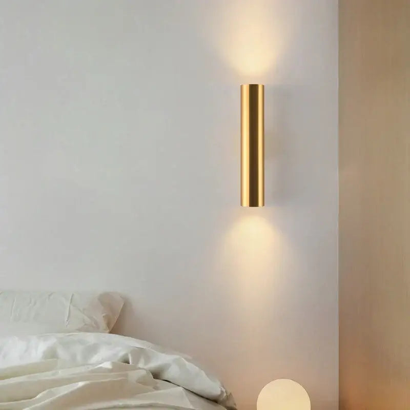Modern brushed gold cylindrical wall lamp with sleek minimalist design for bedroom use featuring led lighting