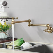 Modern brushed gold pot filler faucet with brass-colored extendable folding spout and ornate handles for kitchen use