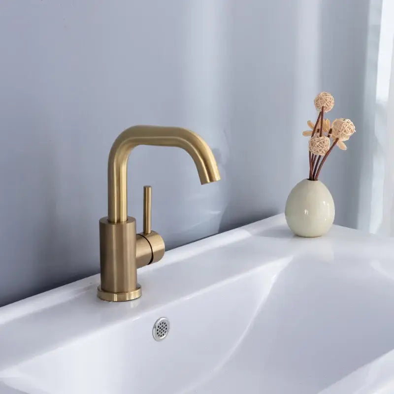 Modern brushed gold basin faucet with single handle and sleek curved spout in brass finish for bathroom use