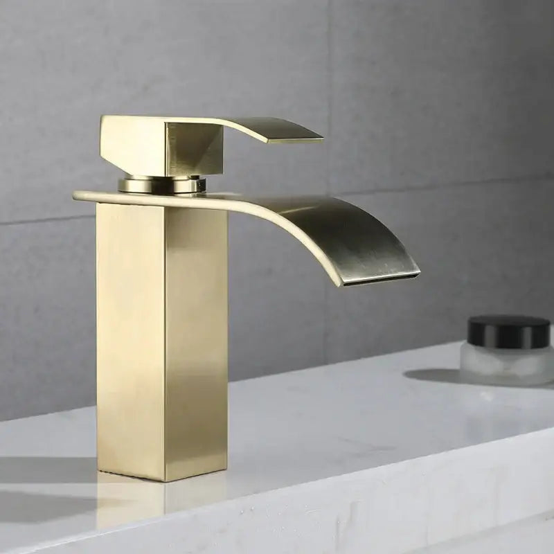 Modern brushed gold stainless steel basin faucet with a sleek rectangular base and arched waterfall spout
