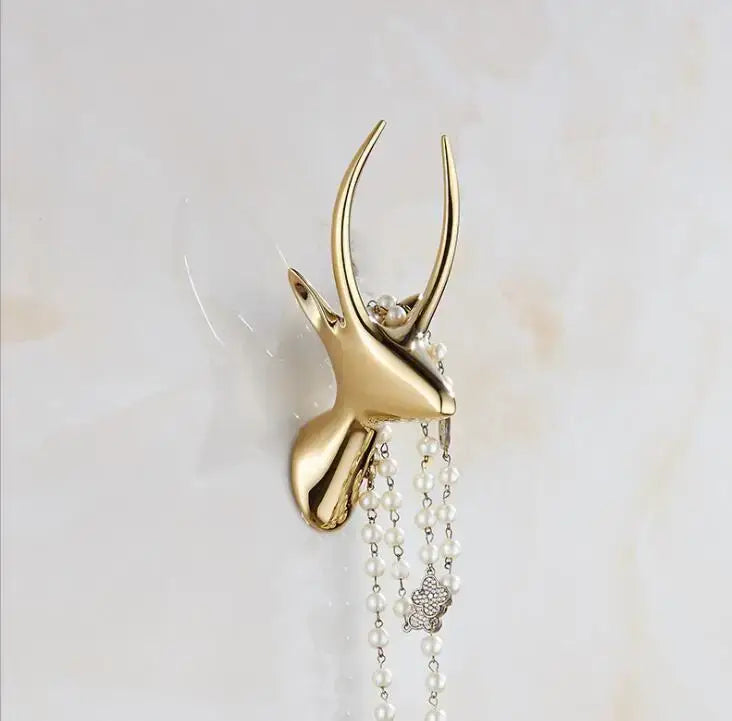 Modern brushed gold stainless steel robe hook shaped like a deer head with polished finish and white pearl strands hanging