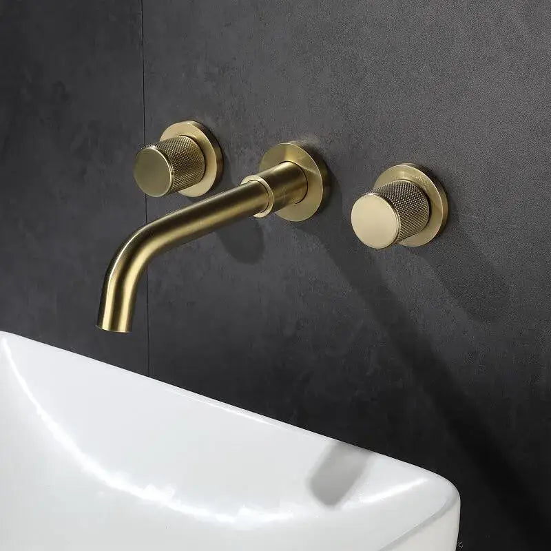 Modern brushed gold wall mount faucet with brass finish, sleek curved spout, and textured circular handles for bathroom use