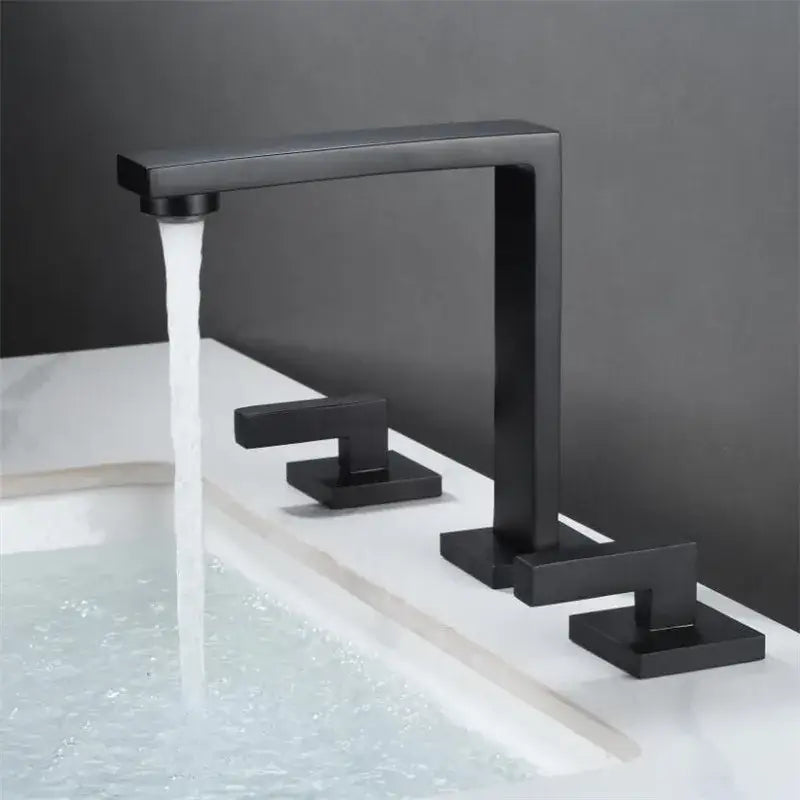 Black matte basin faucet with rectangular spout and three square handles complementing decorbites brushed gold style