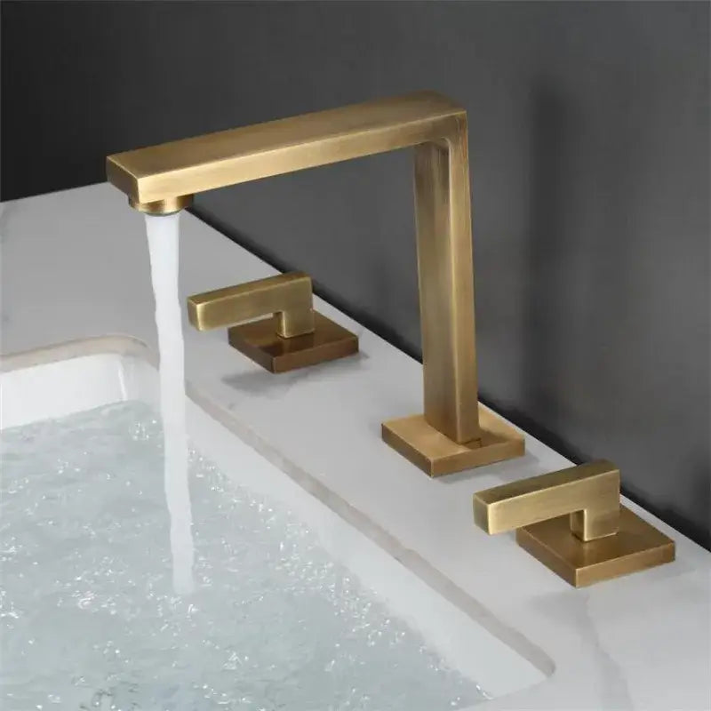 Modern brushed gold basin faucet with sleek rectangular design and three handles for hot cold and overflow control by decorbites