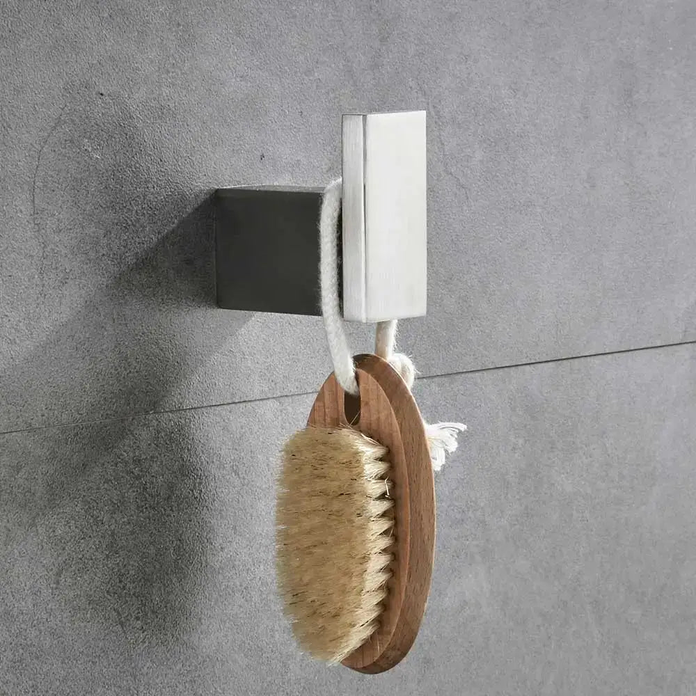 A natural wood handled bath brush with beige bristles hanging on a modern brushed nickel bathroom hardware set hook