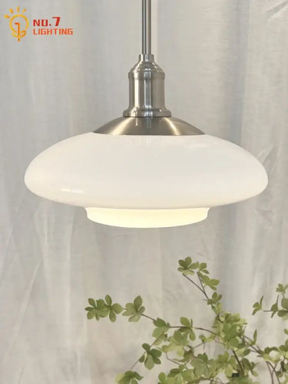 Modern brushed nickel glass pendant light with a brushed steel stem and white opaque shade for kitchen lighting