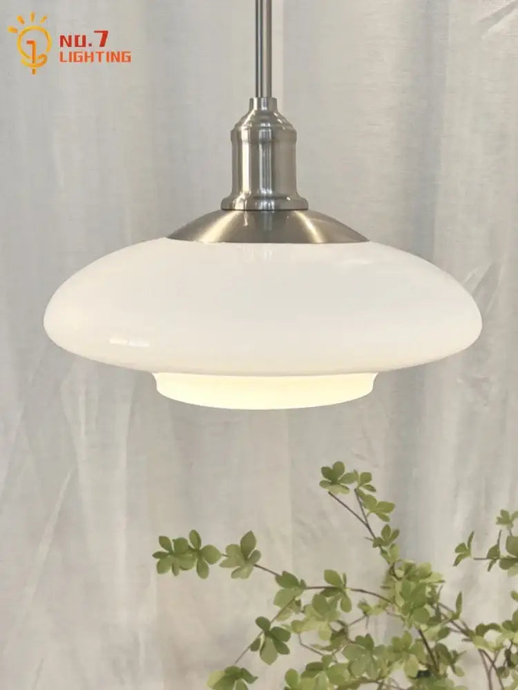 Modern brushed nickel glass pendant light with a brushed steel stem and white opaque shade for kitchen lighting