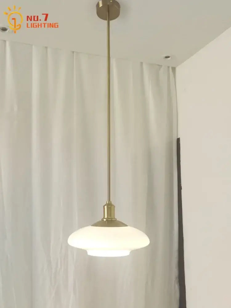 A sleek brass pendant light with frosted glass shade featured among modern brushed nickel glass pendant lights for home decor
