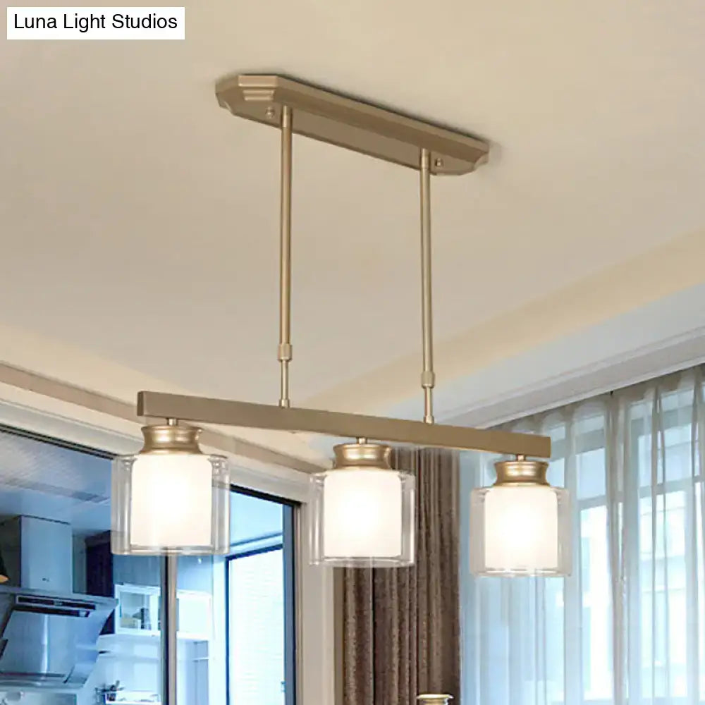 Modern brushed brass pendant light with three clear glass shades and warm white interiors for dining rooms