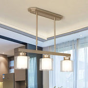 Modern brushed nickel pendant light with three clear glass jars and frosted white shades for dining rooms with traditional gold accents