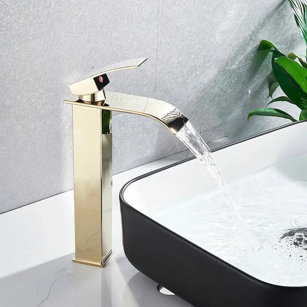 Modern brushed nickel single lever basin faucet with gold-toned waterfall spout and polished metallic finish for bathroom