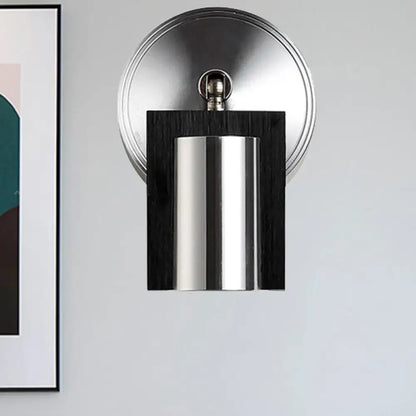 Modern brushed nickel and wood wall sconce with cylindrical metal shade and warm white light for bedroom use