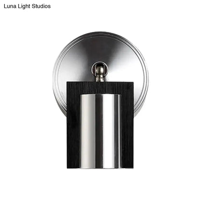 Modern brushed nickel door stop with a sleek metal shade mounted on dark wood panel emitting warm white light