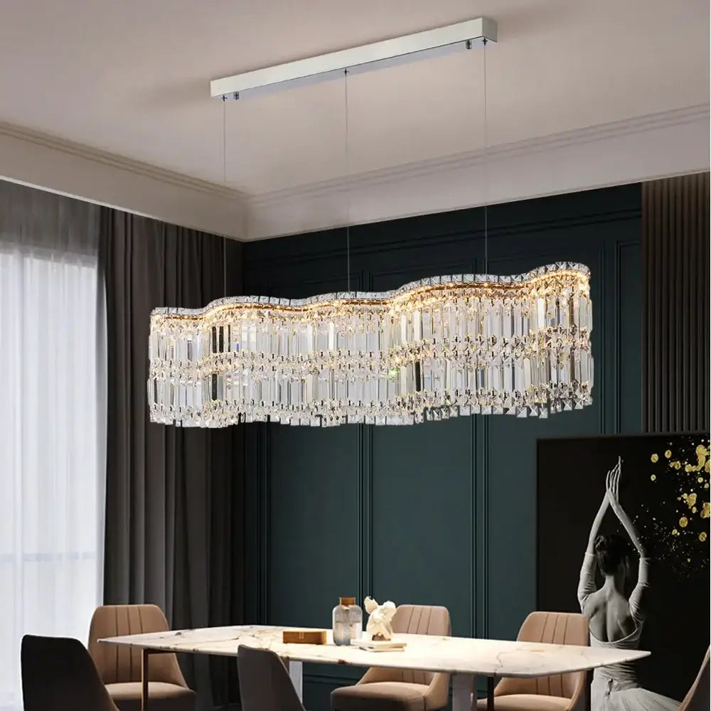 Modern brushed stainless crystal pendant light with sleek chrome frame and warm golden illuminated prisms for dining room