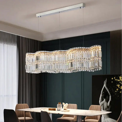 Modern brushed stainless crystal pendant light with sleek chrome frame and warm golden illuminated prisms for dining room