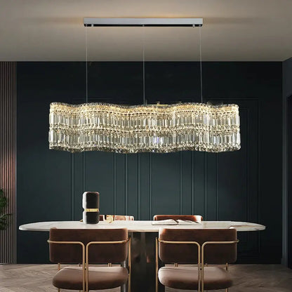 A modern brushed stainless pendant light with clear crystal prisms and a sleek silver ceiling mount for dining rooms
