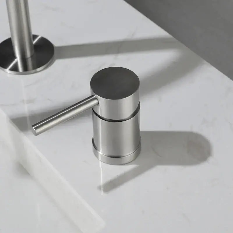 Modern brushed stainless steel soap dispenser with sleek cylindrical body and horizontal lever for kitchen use