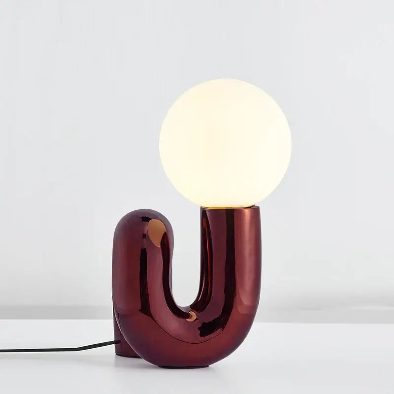 A sleek burgundy glass ball table lamp with a u-shaped ceramic base for modern bedroom decorbites table lamp