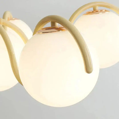 Modern design pendant light featuring cream spherical rounded glass globes with gold-toned metal arms for dining room