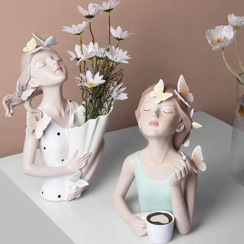 Two ceramic butterfly girl resin sculptures with butterflies in hair holding daisies and coffee cup for living room decor