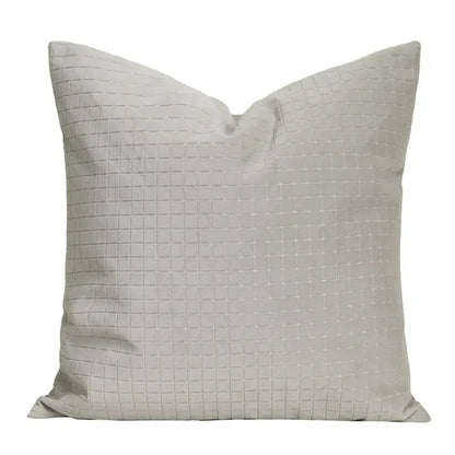 A square light gray cushion with a subtle quilted grid pattern and cappuccino tone geometry embroidery decorbites pillow