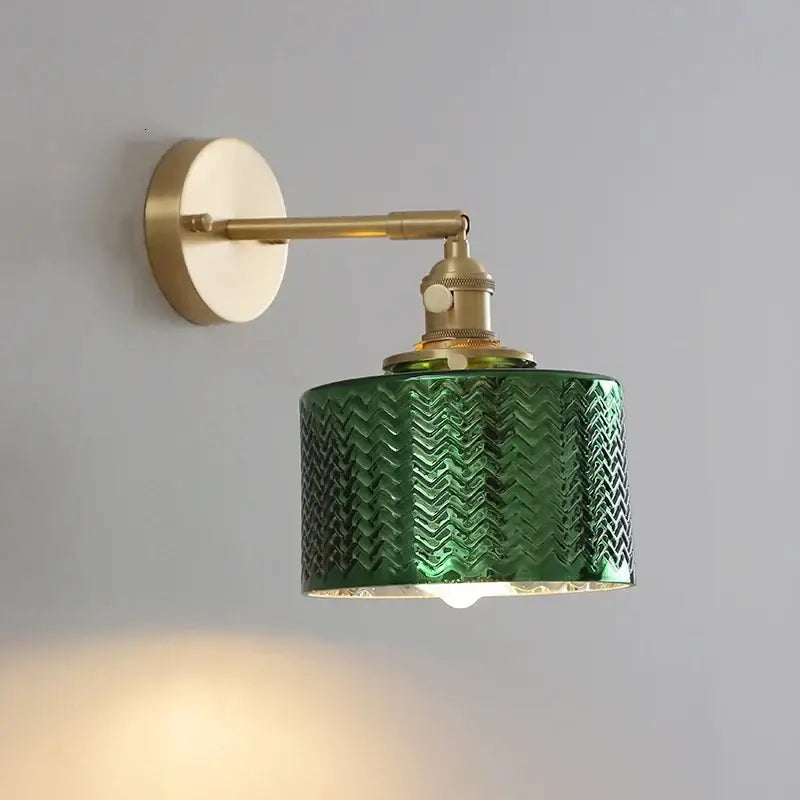A vintage-style wall light with a textured emerald green glass led shade and brass-finished metal components for bedroom use