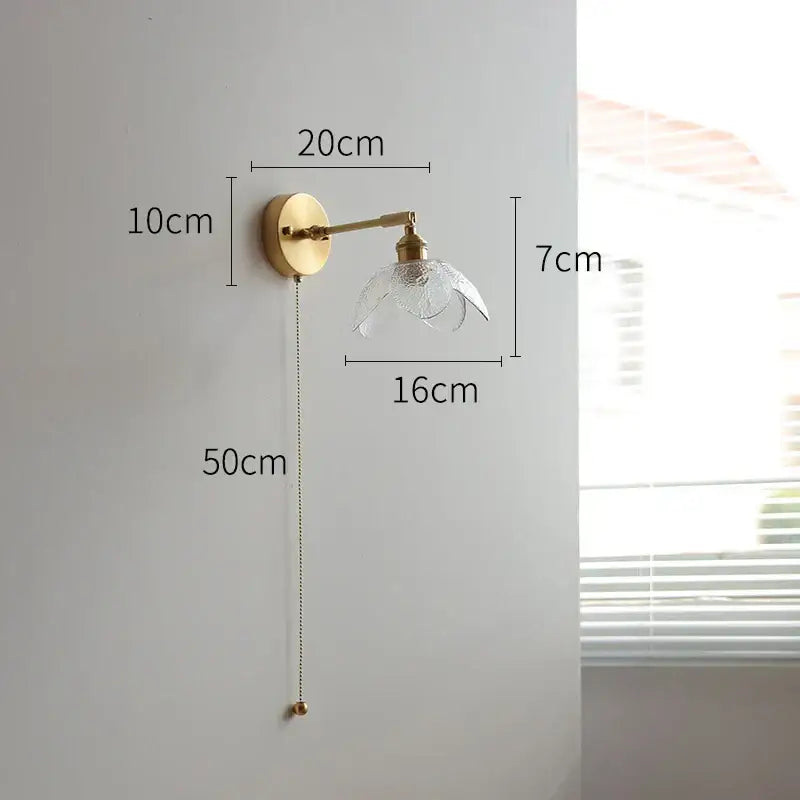 Gold-finished wall light with clear textured glass shade and adjustable arm featuring green glass led for bedroom use
