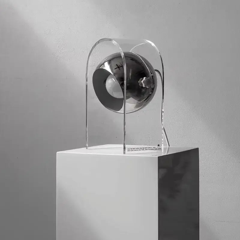 A modern chrome acrylic led desk lamp with a sleek spherical design and transparent acrylic frame for bedroom use