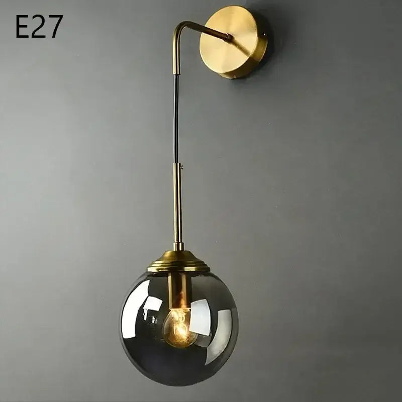 Brass-finished wall lamp with a curved arm and smoked glass ball globe by decorbites for modern living room lighting