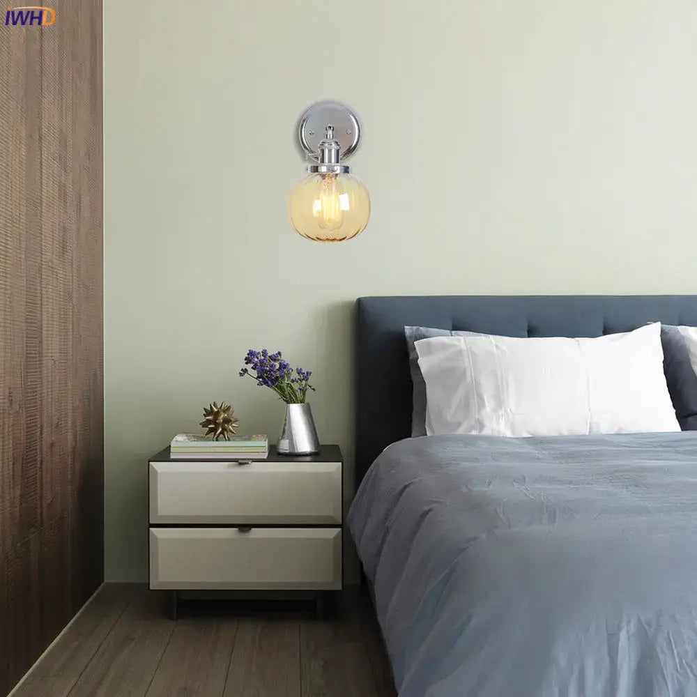Modern chrome wall light featuring a warm amber glass ball globe designed as a bedroom glass ball wall sconce