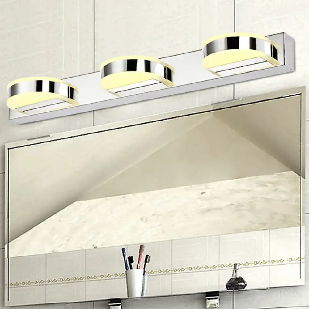 Modern chrome and black geometric wall light with three softly glowing yellow led bulbs in nickel finish for bathroom use