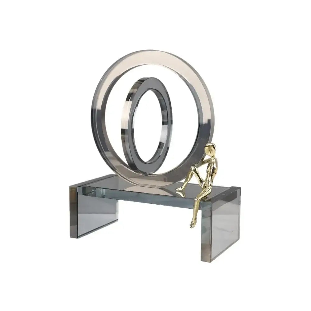 A sleek modern sculpture with polished chrome geometric crystal rings and a small crystal rings golden man figurine