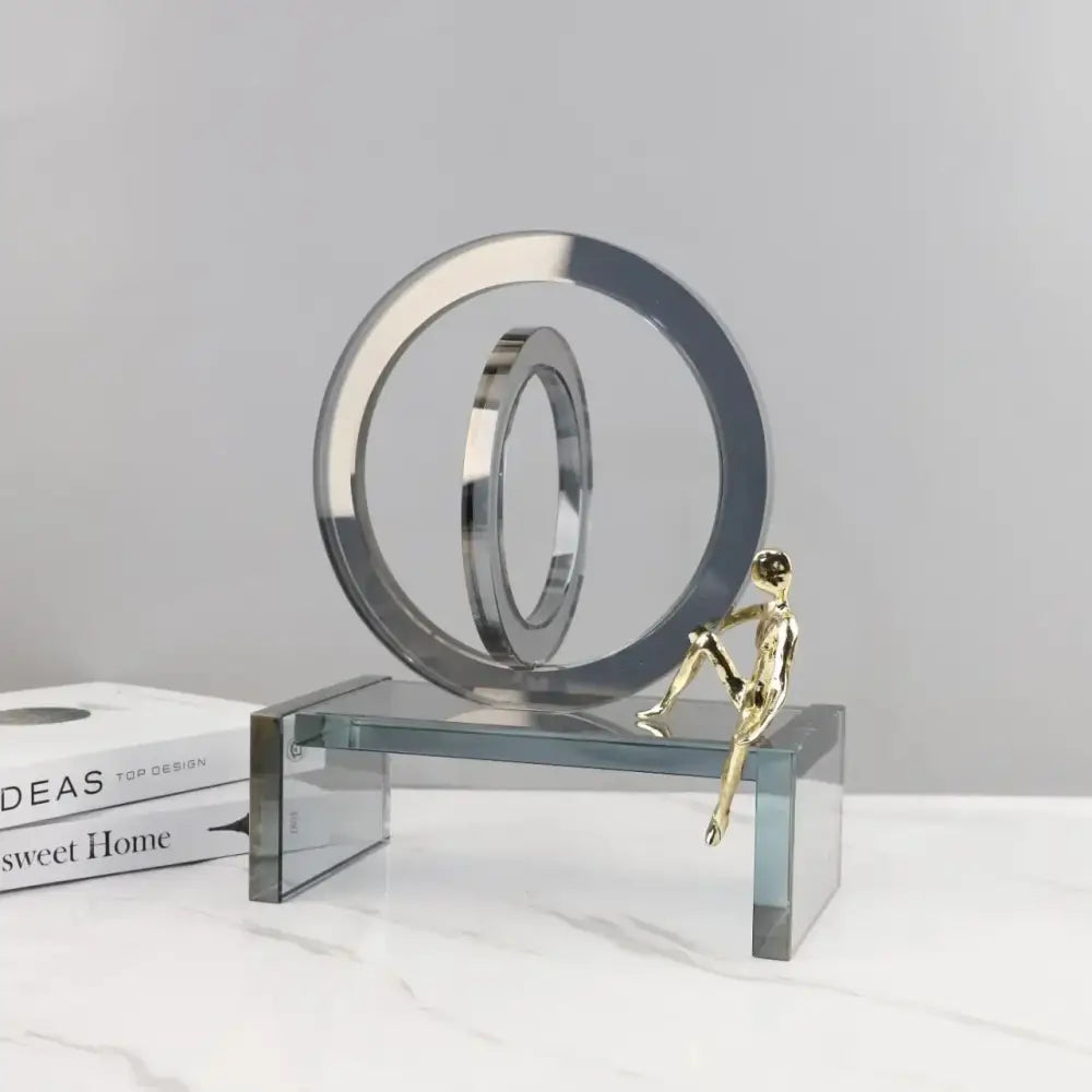 A sleek modern chrome sculpture with geometric crystal rings and a small golden man for living room decor