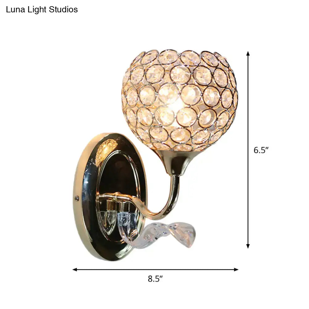 A glamorous gold-toned wall sconce with a spherical crystal globe and twisted glass accent for modern bedroom lighting