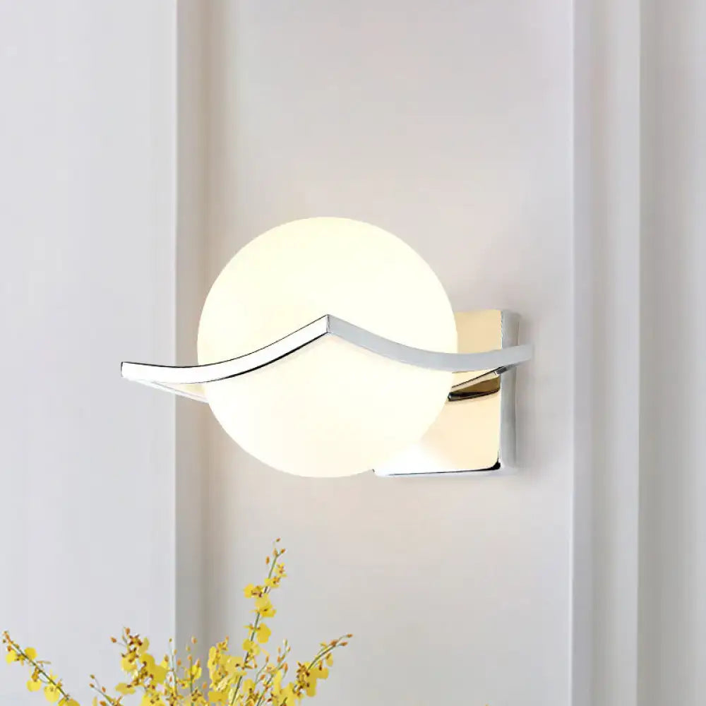 Modern chrome wall sconce with matte white glass globe and sleek curved metal accent for bedroom lighting