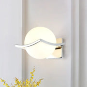 Modern chrome wall sconce with matte white glass globe and sleek curved metal accent for bedroom lighting