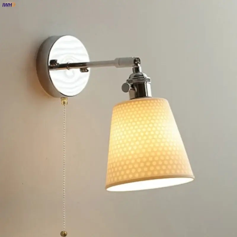 Modern chrome and perforated fabric wall light fixture with warm-toned lampshade and polished chrome arm for bedroom use