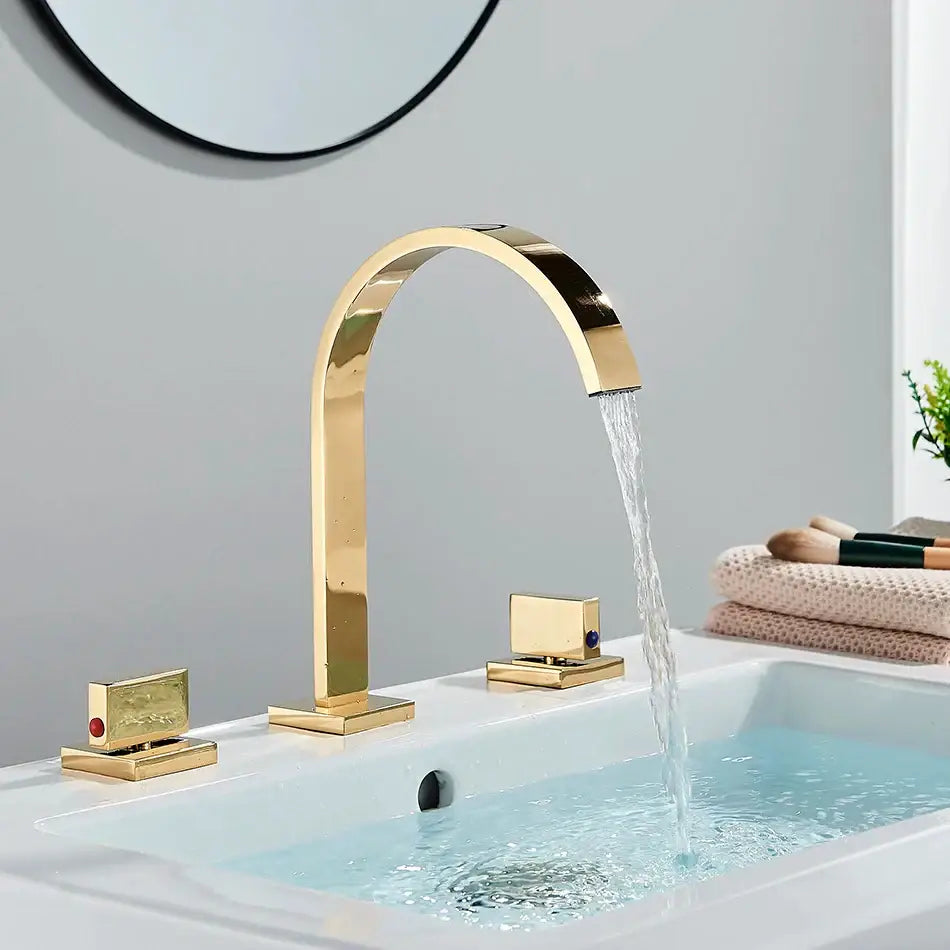 Modern chrome arched dual handle basin faucet with gold-toned finish and three matching square decorbites dual handle controls