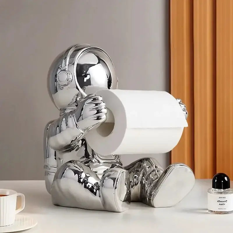 Shiny chrome astronaut tissue box figurine holder designed to hold a roll of tissue for living room use
