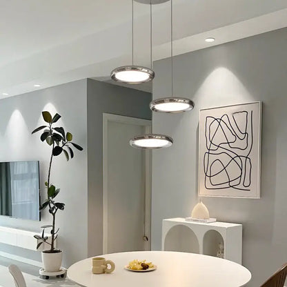 Three modern chrome circular dining pendant led lights with sleek frames and soft white illumination for kitchen decorbites