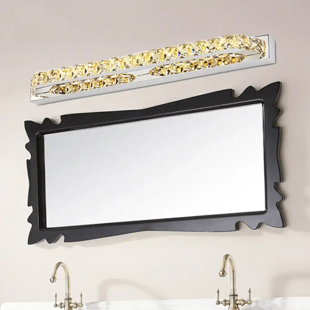 A modern chrome clear amber crystal led vanity light bathroom sconce above a sleek rectangular mirror with a black frame