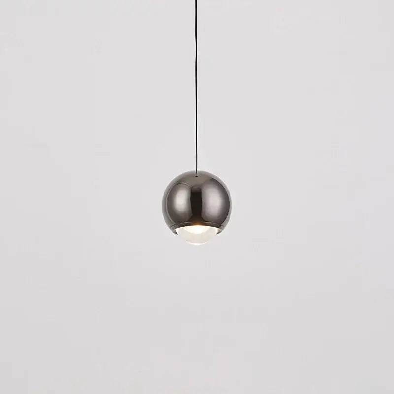 A modern chrome and copper ball pendant light with a brushed metallic finish and integrated warm glow for dining room