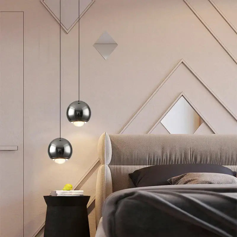Two sleek polished chrome ball pendant lights hang in a dining room as a modern chrome pendant light chandelier