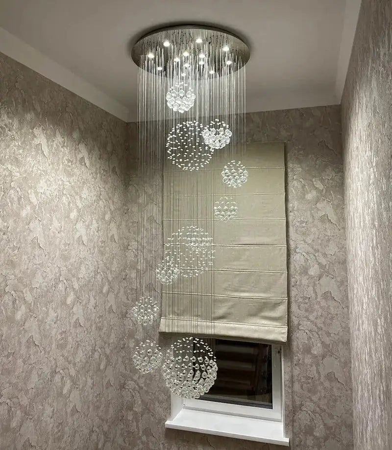 A modern chrome crystal ball design chandelier set with circular metallic base and cascading clear glass orbs for staircases