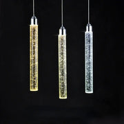 Three modern crystal led pendant lights with chrome tops and glass bodies glowing in gold warm white and cool white hues