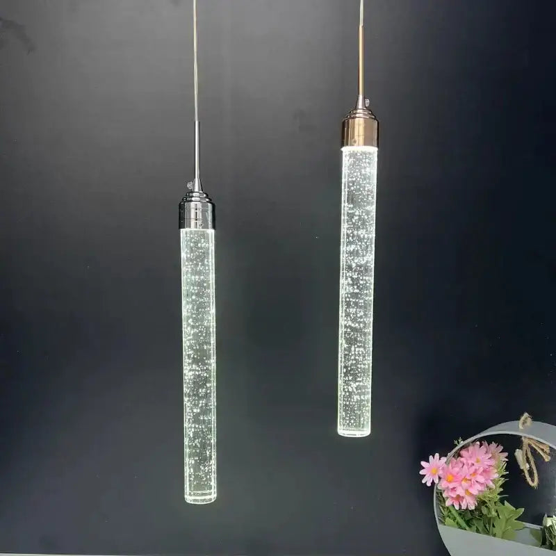 Two modern chrome decorbites crystal led pendant lights with clear glass bodies and metallic tops for dining room decor